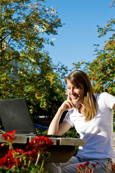 Счастливая девушка на улице с ноутбуком — стоковое фото
