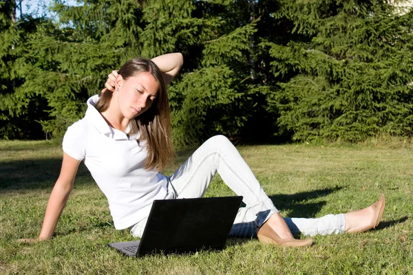 Bir çim üstünde a laptop ile gülümseyen kız — Stok fotoğraf