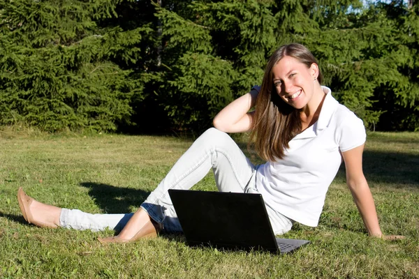 Uśmiechnięte dziewczyny z laptopa na trawnik — Zdjęcie stockowe