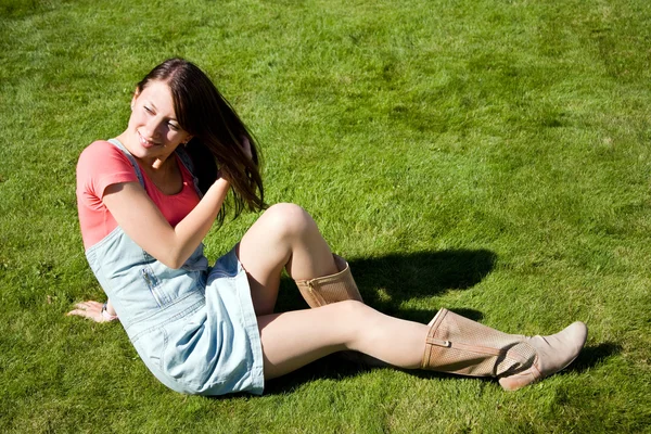 Schöne gesunde junge Frau auf dem grünen Gras liegend — Stockfoto