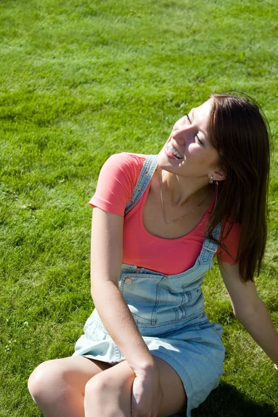 Mooie gezonde jonge vrouw liggend op het groene gras — Stockfoto