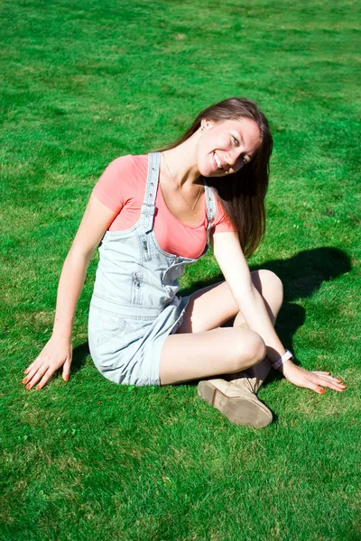 Yeşil çimenlerin üzerinde oturan güzel sağlıklı genç kadın — Stok fotoğraf
