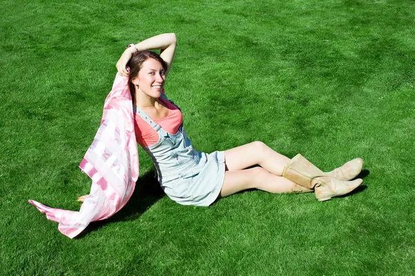 Gelukkig jonge brunette met een zakdoek rusten op het gazon in — Stockfoto