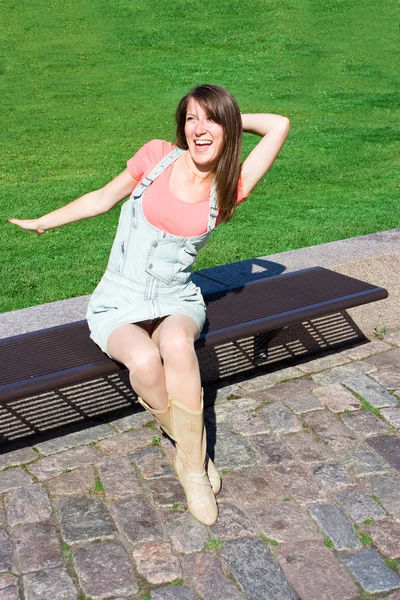Genç kadın açık yaz gününde bir parkta bankta rahatlatıcı — Stok fotoğraf