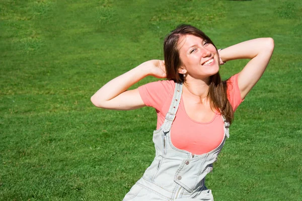 Bela jovem estudante no fundo de um gramado verde — Fotografia de Stock