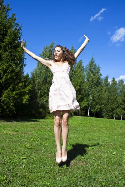 Mooie jonge gelukkig vrouw onder de blauwe hemel. Stockfoto