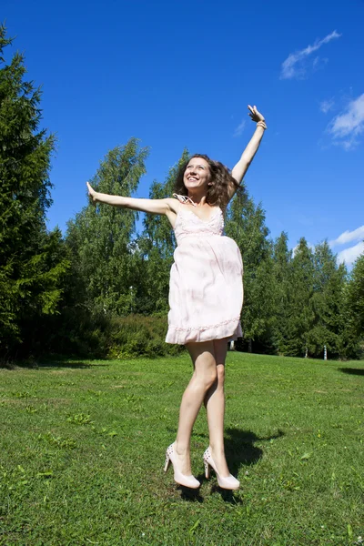 Mooie jonge gelukkig vrouw onder de blauwe hemel. Stockfoto
