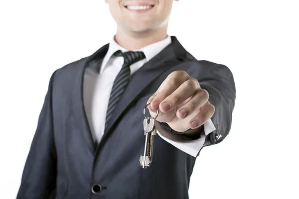 Бизнесмен с ключом от дома в руке изолирован на белом — стоковое фото