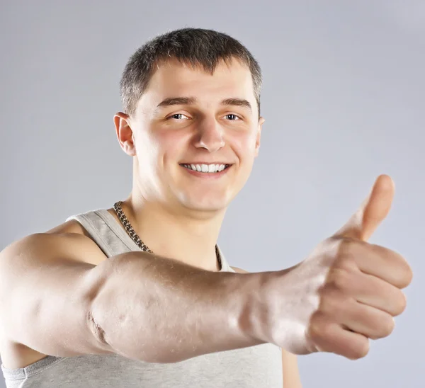 Lächelnder junger Mann mit erhobenem Daumen — Stockfoto