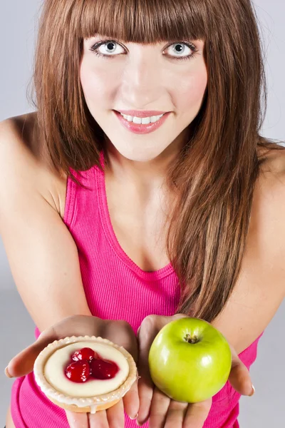 Mujer con manzana y pastel en las manos — Foto de Stock