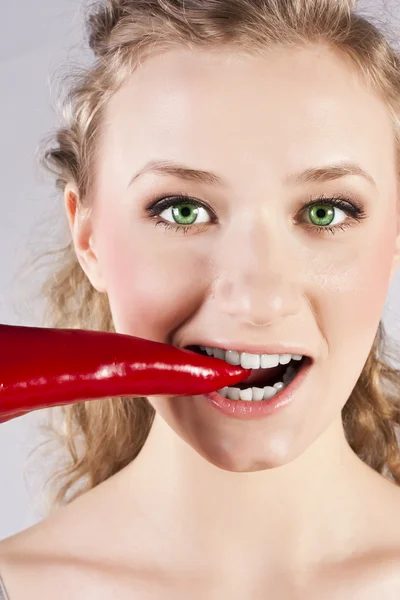 Vacker kvinna tänder äta red hot chili peppar — Stockfoto