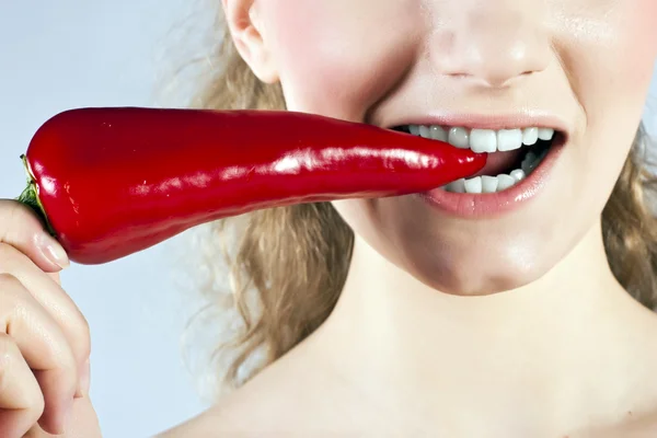 Mooie vrouw tanden eten van red hot chili peper — Stockfoto
