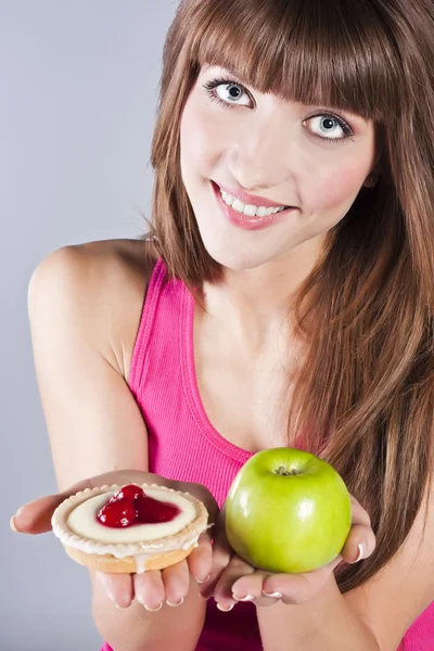 Kvinna med äpple och tårta i händer — Stockfoto