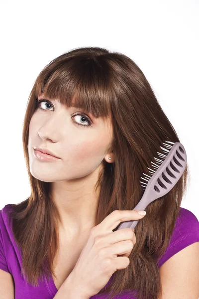 Brunette brushing her hair, in studio — Stock Photo, Image