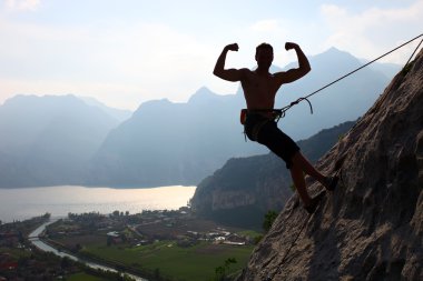 Silhouette of a rock climber flexing biceps clipart