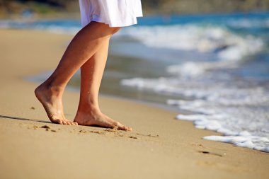 Kumsalda yürüyen genç bir kadın Resim kırpılmış