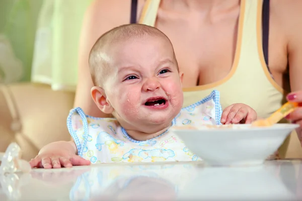 Matka karmienia płacz chłopiec z łyżeczką — Zdjęcie stockowe
