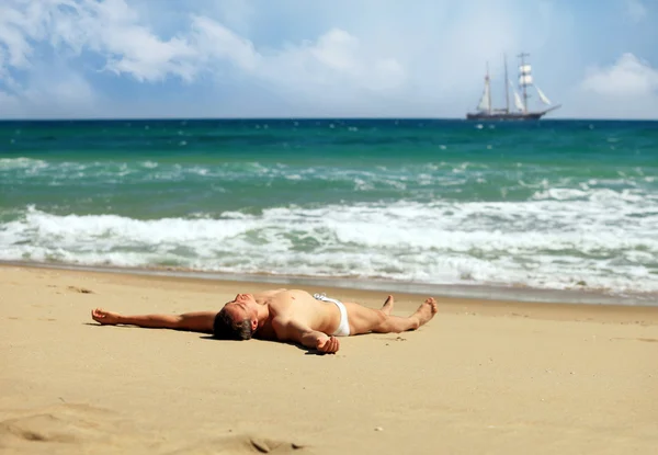Young man sunbathing at a beach — Stock Photo, Image