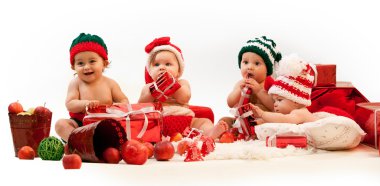 Four babies in xmas costumes playing among gifts clipart