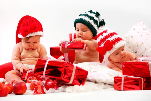 Three babies in xmas costumes playing with gifts — Stock Photo, Image