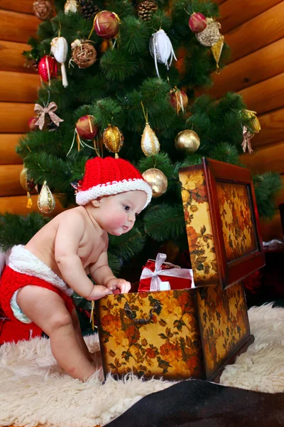 Cute baby boy looking into case with gifts — Stock Photo, Image