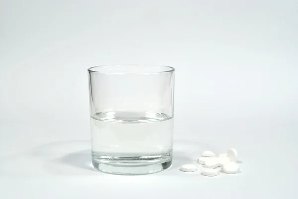 Het glas van water en wat pillen — Stockfoto