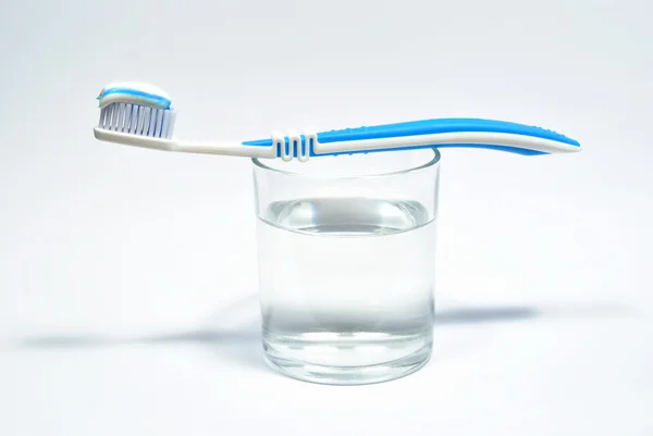 Glas vatten och tandborste med tandkräm Stockfoto