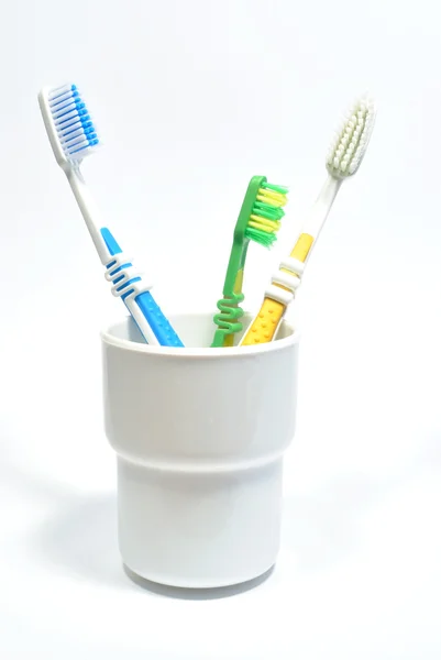 Tres cepillos de dientes de toda la familia en vidrio plástico Imagen de stock