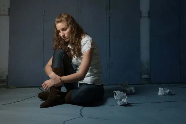 Trauriges einsames Mädchen, das in der Dunkelheit auf Mehl sitzt — Stockfoto