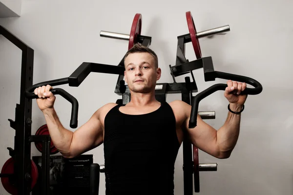Homem fazendo treinamento de fitness na máquina com pesos em um ginásio — Fotografia de Stock