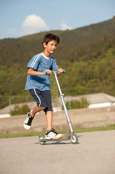 Young boy in blue dress on scooter — Stock Photo, Image