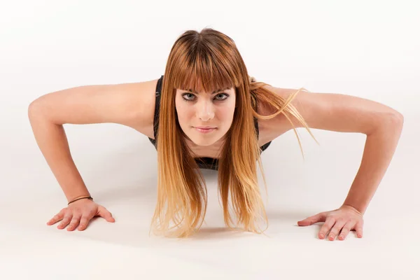 Aantrekkelijke jonge vrouw doen pushups op witte achtergrond — Stockfoto