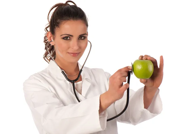 Fiatal orvos sztetoszkóppal, aki almát hallgat. — Stock Fotó