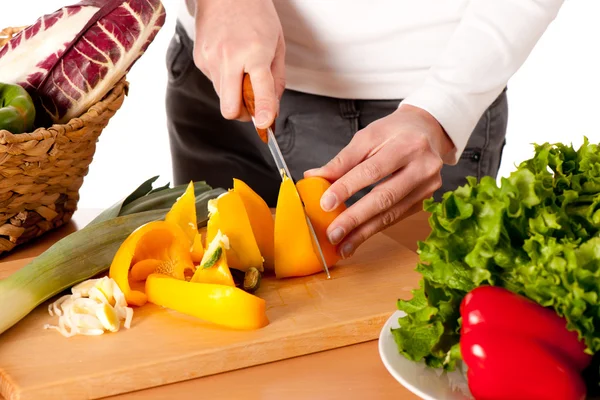 stock image Attractive young woman cutting vegetables and preparing meal