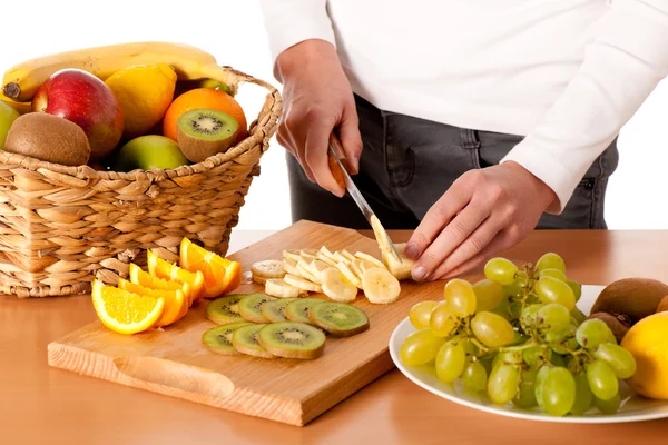 stock image Attractive young woman cuting fruits and preparing fruit salad