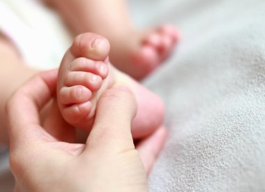 Closeup portrait of mother massaging small baby foot clipart