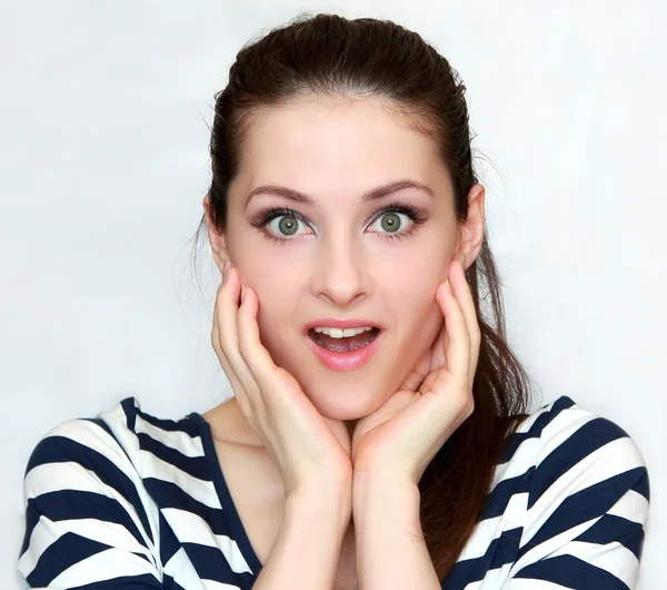 Beautiful young happy woman holding hands to face in surprise Stock Picture