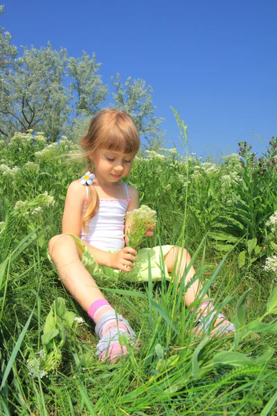 Klein meisje zit in het gras — Stockfoto