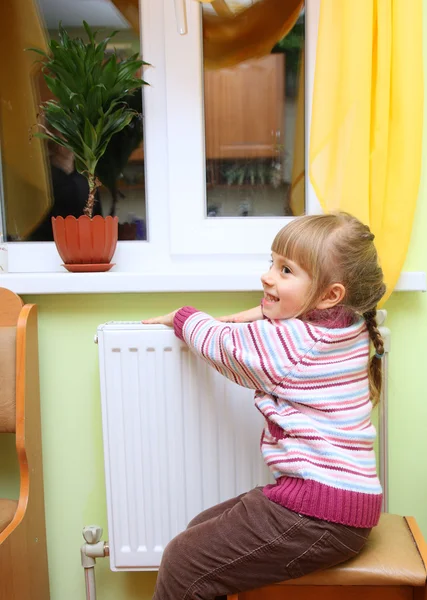 Chica caliente las manos cerca del radiador . —  Fotos de Stock
