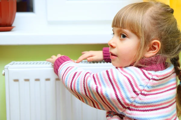 Menina quente as mãos perto do radiador — Fotografia de Stock