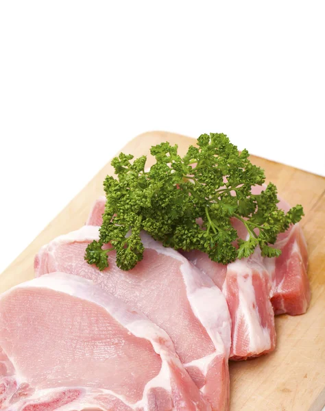 Trozos de carne y racimo de pasrley sobre tabla de madera — Foto de Stock
