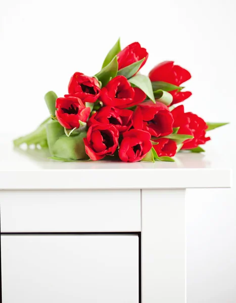 Red tulips lying on white table — Stock Photo, Image