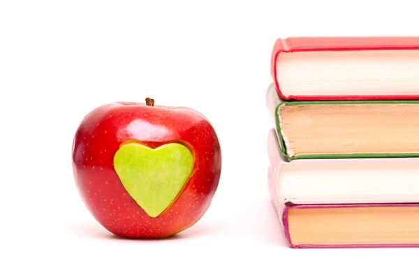 Apple with green heart and stack of books — Stock Photo, Image