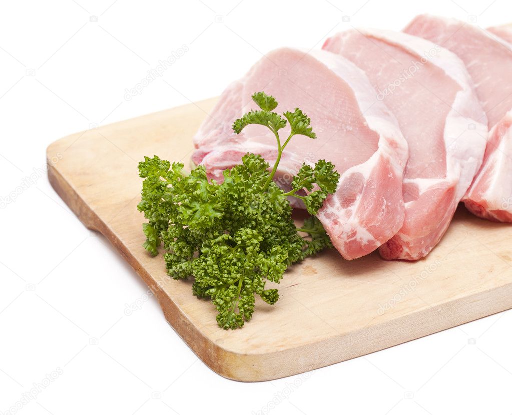 Pieces of meat and bunch of parsley on wooden board