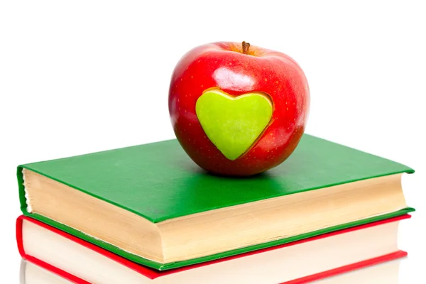 Apfel mit grünem Herz auf Bücherstapel Stockbild