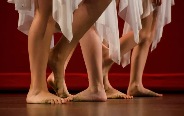 Pies de los bailarines de ballet frente a una pared roja — Foto de Stock