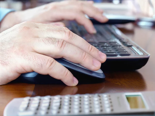 Человеческие руки на компьютерной мыши и клавиатуре — стоковое фото