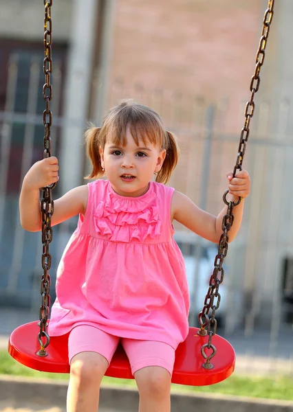 Счастливая маленькая девочка на качелях — стоковое фото