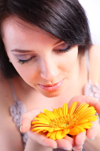 Young woman smelling an orange flower — Stock Photo, Image