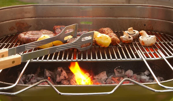 Barbecue avec viande, légumes et pinces en métal — Photo
